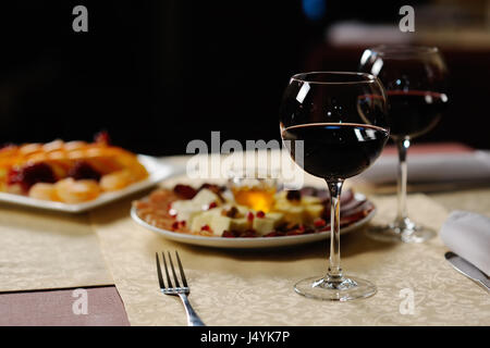 Due bicchieri di vino rosso sullo sfondo dei piatti in r Foto Stock