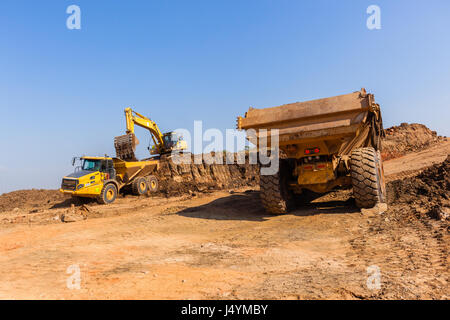 Costruzioni industriali earthworks macchina livellatrice caricamento della terra in grandi autocarri Foto Stock