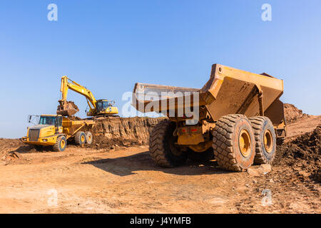 Costruzioni industriali earthworks macchina livellatrice caricamento della terra in grandi autocarri Foto Stock