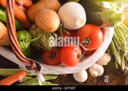 Assortimento di verdure in un cesto di vimini sul suolo. Composizione orizzontale. Vista superiore Foto Stock