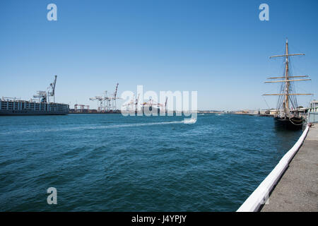 Dock commerciale con grandi gru, SS Leeuwin II tall ship e in barca nel fiume Swan entrata sotto un cielo blu chiaro in Fremantle, Western Australia. Foto Stock