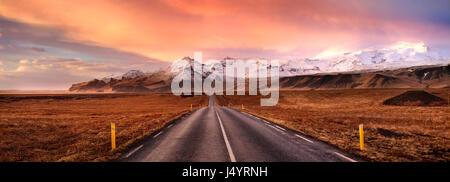 Orizzonte su strada e le montagne coperte di neve, Islanda Foto Stock