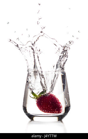 Una fragola è caduta in un bicchiere di acqua con un grande splash Foto Stock