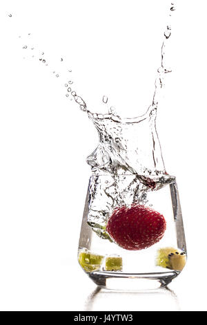 Una fragola è in calo il cocktail in un bicchiere di acqua con spruzzi e cubo di kiwi Foto Stock