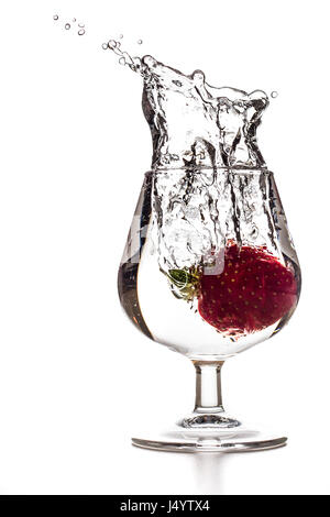 Una fragola è in calo il cocktail in un bicchiere di acqua con splash Foto Stock