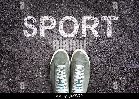 Sport di parola scritta su strada asfaltata con scarpe da ginnastica, sport concept Foto Stock