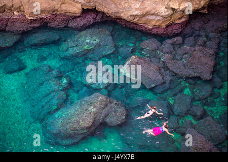 Vista da scogliere di roccia di nuotatori ad esplorare le cristalline acque del Mediterraneo di una baia al largo di Dubrovnik, Croazia Foto Stock