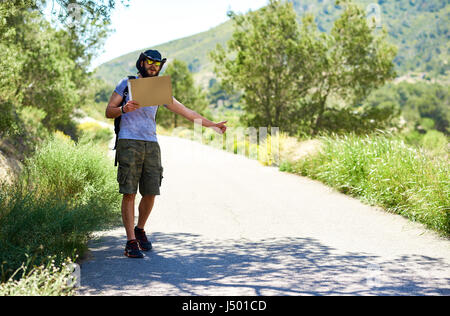 Sollevatore-escursionismo viaggiatore con un cartone vuoto segno su una strada di montagna. Il bilancio di viaggio. Arresto automatico Foto Stock