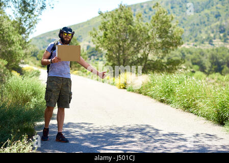 Sollevatore-escursionismo viaggiatore con un cartone vuoto segno su una strada di montagna. Il bilancio di viaggio. Arresto automatico Foto Stock