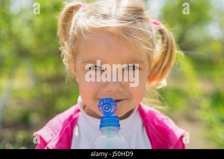 Piccola ragazza carina di bere acqua da bottiglie di plastica. sunny foto Foto Stock