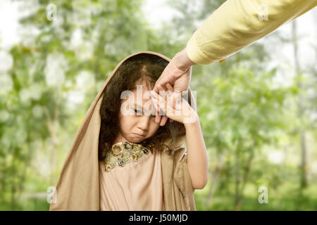 Musulmani asiatici bambino baciare la mano ai genitori per il tradizionale atto di rispetto all'aperto Foto Stock