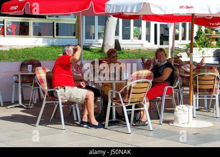 I turisti in un momento di relax a un cafe' sul marciapiede lungo la promenade, Torrox Costa, provincia di Malaga, Andalusia, Spagna, Europa occidentale. Foto Stock