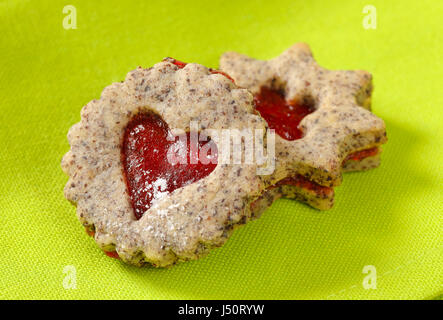 Biscotti frollini con marmellata il deposito su sfondo verde Foto Stock