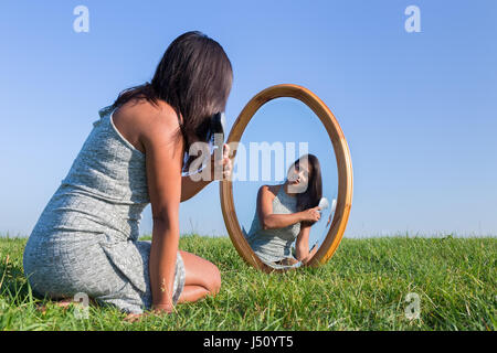 Donna colombiano spazzolando i suoi capelli neri in specchio esterno Foto Stock