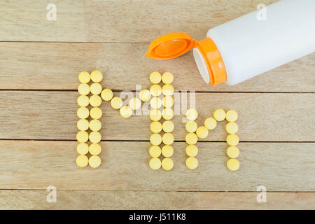 Pillole di giallo forma di formatura a Mn alfabeto su uno sfondo di legno Foto Stock