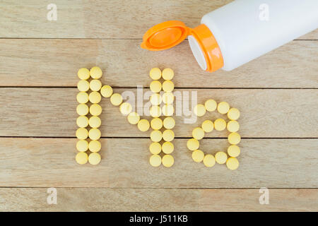 Pillole di giallo forma di formatura a Na alfabeto su uno sfondo di legno Foto Stock