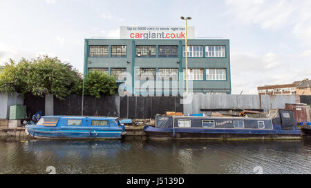 Narrowboats tradizionale ormeggiato sul Grand Union Canal accanto alla macchina gigante unità industriali e magazzini alla Vecchia Quercia comune nella zona ovest di Londra. Foto Stock