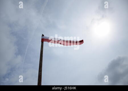 Bandiera polacca battenti sul pennone nel cielo nuvoloso Foto Stock