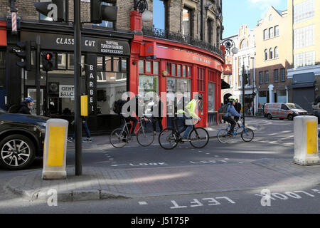 La gente in bicicletta per lavorare in bicicletta passa accanto a piccoli negozi all'angolo tra St John Street e Clerkenwell Road a Londra EC1 Inghilterra UK KATHY DEWITT Foto Stock