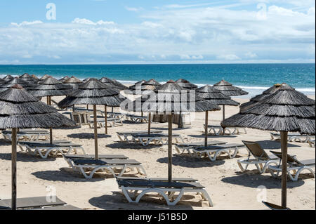 Spiaggia deserta con sedie a sdraio e ombrelloni Foto Stock