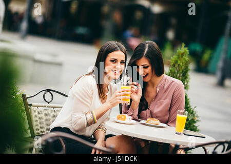 Ritratto di giovane e bella donne mangiare torta al cafè all'aperto Foto Stock