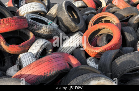 Varietà di rosso bianco e nero dei rifiuti pneumatici auto accatastati in una grande pila Foto Stock