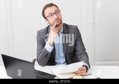 Malinconici imprenditore alla scrivania in ufficio Foto Stock