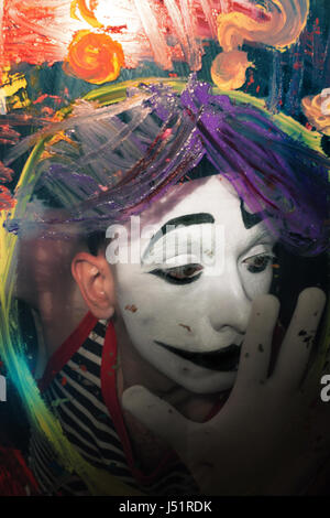 La faccia di Mime dietro il vetro con multi-colore di macchie di vernice closeup Foto Stock