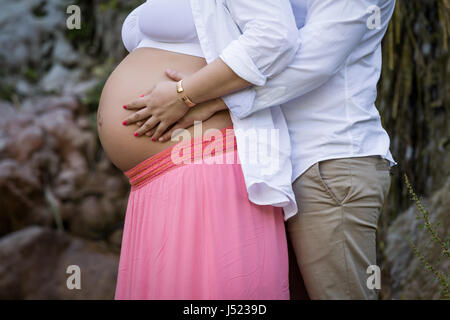 L'uomo abbraccia il ventre di sua moglie incinta. Felice e giovane coppia in gravidanza. Foto Stock