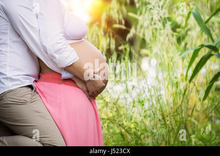 L'uomo abbraccia il ventre di sua moglie incinta. Felice e giovane coppia in gravidanza. Foto Stock
