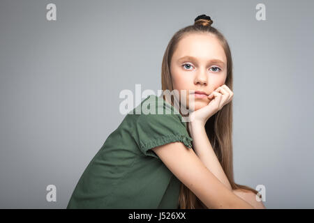 Ritratto di giovane bella ragazza su sfondo grigio. donna vestita in verde T-shirt Foto Stock