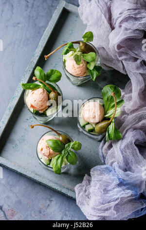 Verrines antipasto con salmone pate, caviale rosso, cetriolo, crema di formaggio, erbe, capperi in bicchieri serviti sul vassoio in legno, tessile gauz su grigio blu t Foto Stock