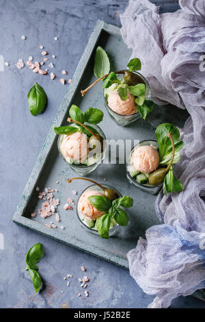 Verrines antipasto con salmone pate, caviale rosso, cetriolo, crema di formaggio, erbe, capperi in bicchieri serviti sul vassoio in legno, tessile gauz, rosa sale e b Foto Stock