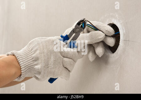 Mani di elettricista guanti in fili di taglio con clippers Foto Stock