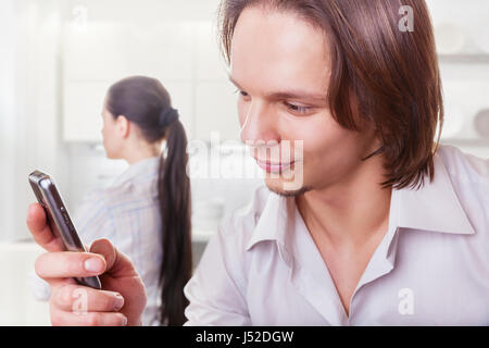 Coppia giovane dopo litigare. Uomo che guarda con un sorriso sul tuo telefono in primo piano Foto Stock