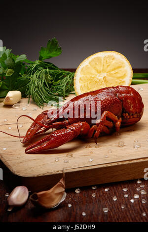 Bollito di gamberi con sale marino, aglio, limone, prezzemolo e l'aneto sul tagliere di legno Foto Stock