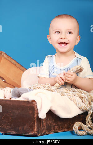 Little Boy in un marinaio suit ride seduti su uno sfondo blu Foto Stock
