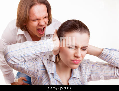 Enraged uomo grida al giovane donna. Donna che copre le sue orecchie con le mani. Isolato su sfondo bianco Foto Stock