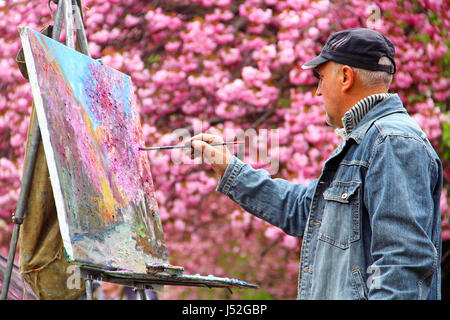 UZHGOROD, Ucraina - 14 Aprile 2017: un artista dipinge un quadro di fioritura sakura albero nel centro di Uzhgorod Foto Stock