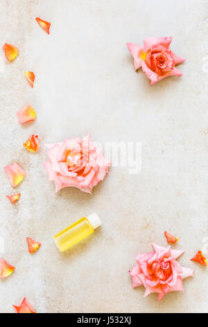 Aromaterapia rose olio per massaggi. Fiori di rose e oli essenziali, spa e aromaterapia ancora in vita. Vista superiore, superficie rustico, spazio vuoto Foto Stock