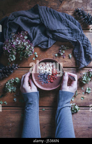 Donna mangiare frullato al cioccolato ciotola con noci del Brasile, goji bacche e cacao naselli Foto Stock