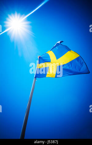 Bandiera della Svezia contro il cielo blu sotto il sole Foto Stock