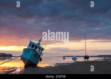 Un tramonto mozzafiato di scena a Instow Beach, North Devon. Le barche sono sulla spiaggia con la bassa marea con un vivido sky. Foto Stock