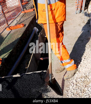 I lavoratori di una strada in costruzione sito con alta visibilità pantaloni e una pala di lavoro in mano Foto Stock