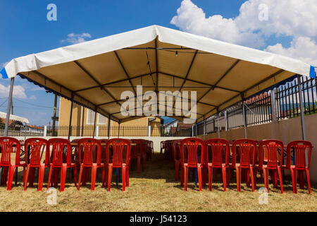 Intrattenimento bianco tenda rossa con sedie di plastica in giardino Foto Stock