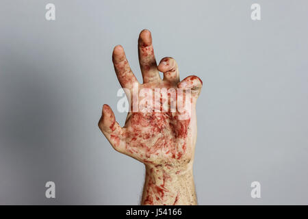 Bloody mano davanti a uno sfondo grigio Foto Stock