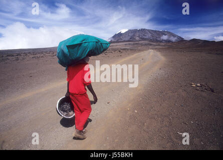 Porter portando safari stuff attraversando il Sadlle sul modo di Mt. Kilimanjaro, il punto più alto in Africa con 5895 metri sopra il livello del mare, Tanzania Foto Stock