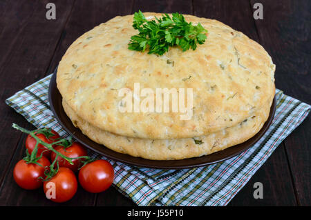 Una spessa flapjack - pane pita con verdi su legno scuro dello sfondo. Un tradizionale piatto asiatico. Foto Stock