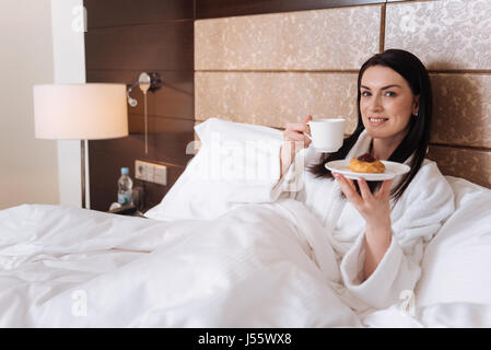 Felice donna attraente tenendo il piacere nella sua prima colazione Foto Stock