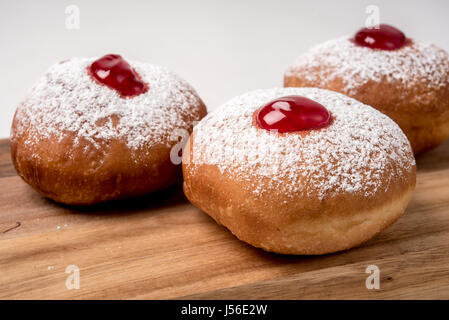 Sufganiyah (sufganiyot) una tradizionale ciambella ebraica mangiato durante Hanukkah confettura rossa e zucchero in polvere. Su sfondo bianco Foto Stock